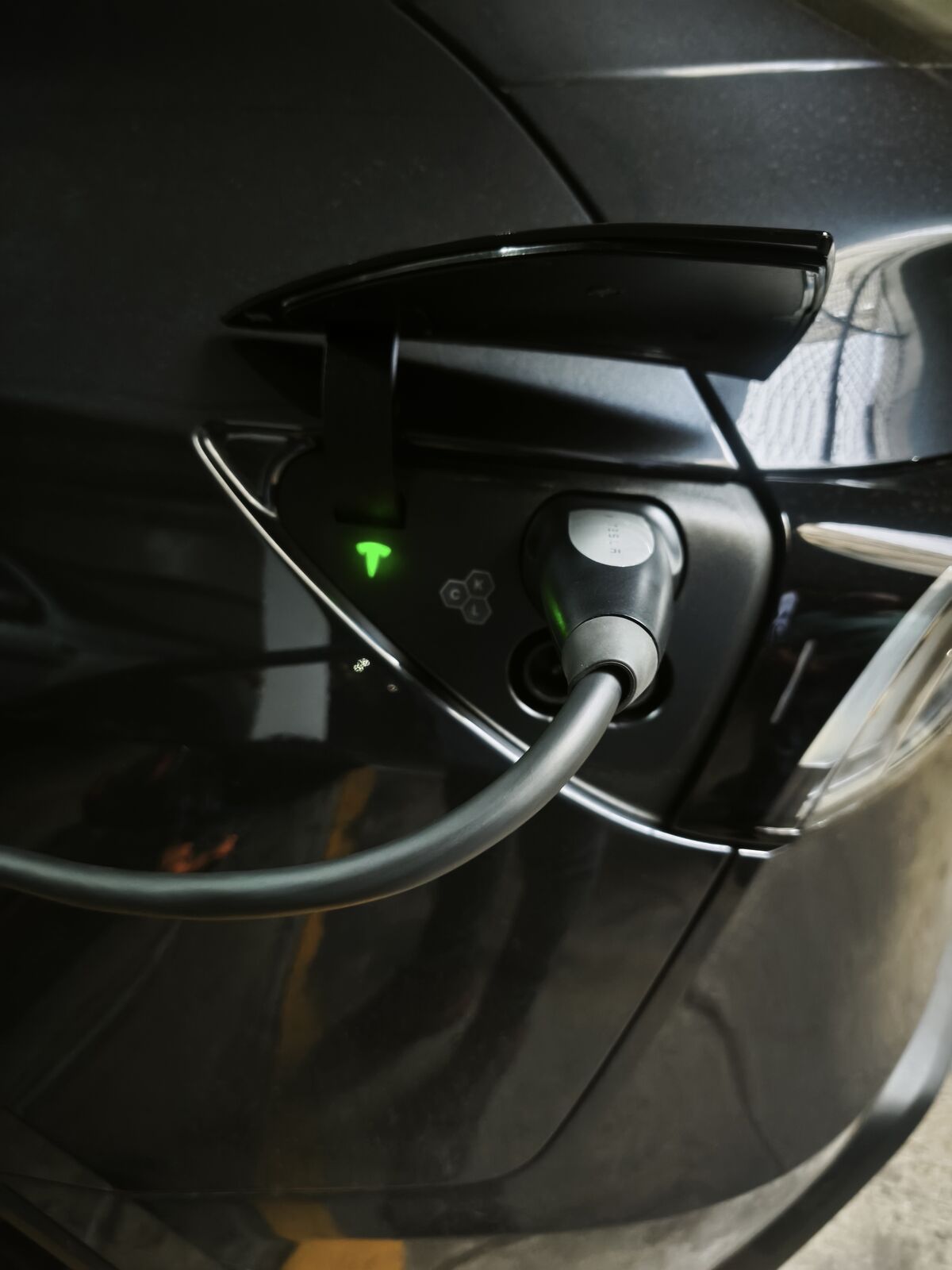 Puerto de carga de un vehículo eléctrico con el conector puesto y la luz verde encendida